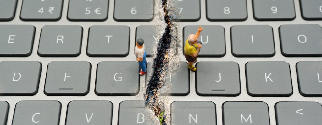 Internet Confrontation.digital divide.The keyboard is split by the cracks that separate the opposites.Social Divide.Divided world.conflicts.cyberbullying.