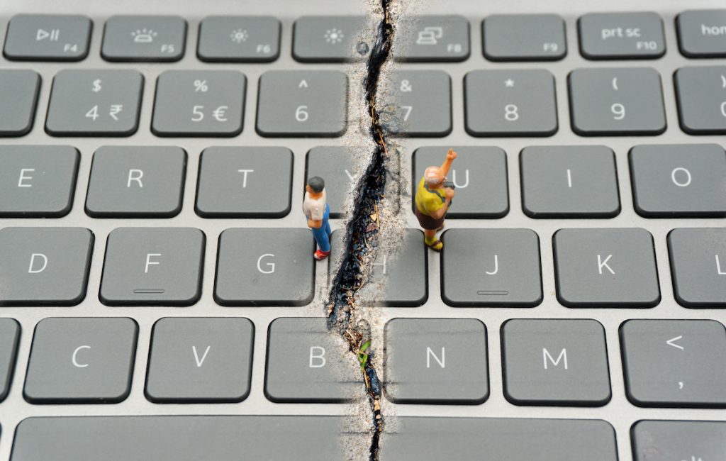 Internet Confrontation.digital divide.The keyboard is split by the cracks that separate the opposites.Social Divide.Divided world.conflicts.cyberbullying.
